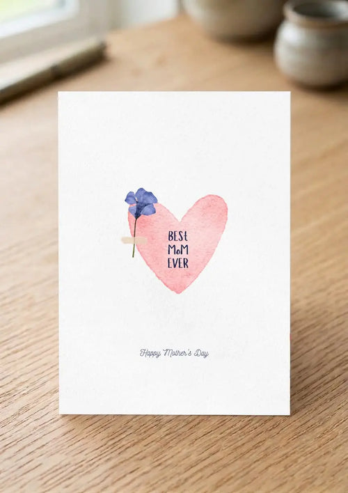 Card with a pink heart and blue flowers on a wooden surface