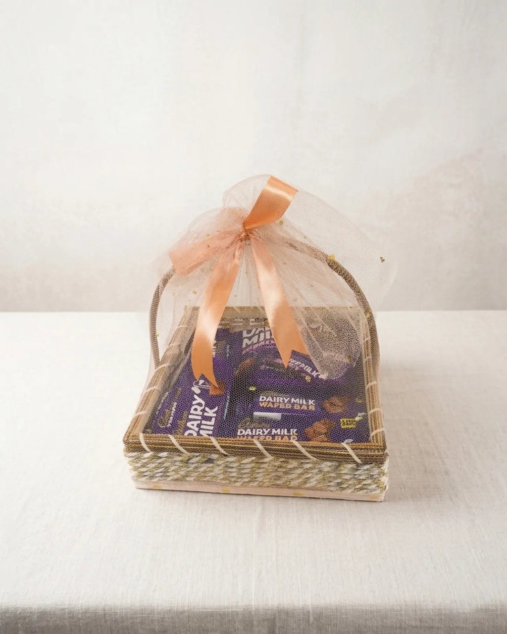 Woven 10x10 basket with Cadbury Dairy Milk Wafer Bars, Dairy Milk bars and Dairy Milk Bubbly wrapped in peach organza gift hamper by The Love Language Pakistan