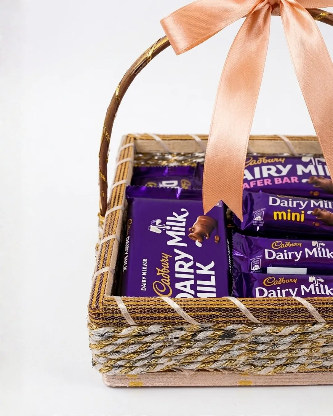 Basket of Cadbury Dairy Milk chocolate bars with a pink ribbon on a white background
