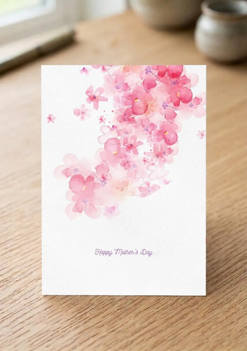 Greeting card with pink floral design and 'Happy Mother's Day' text on a wooden surface.