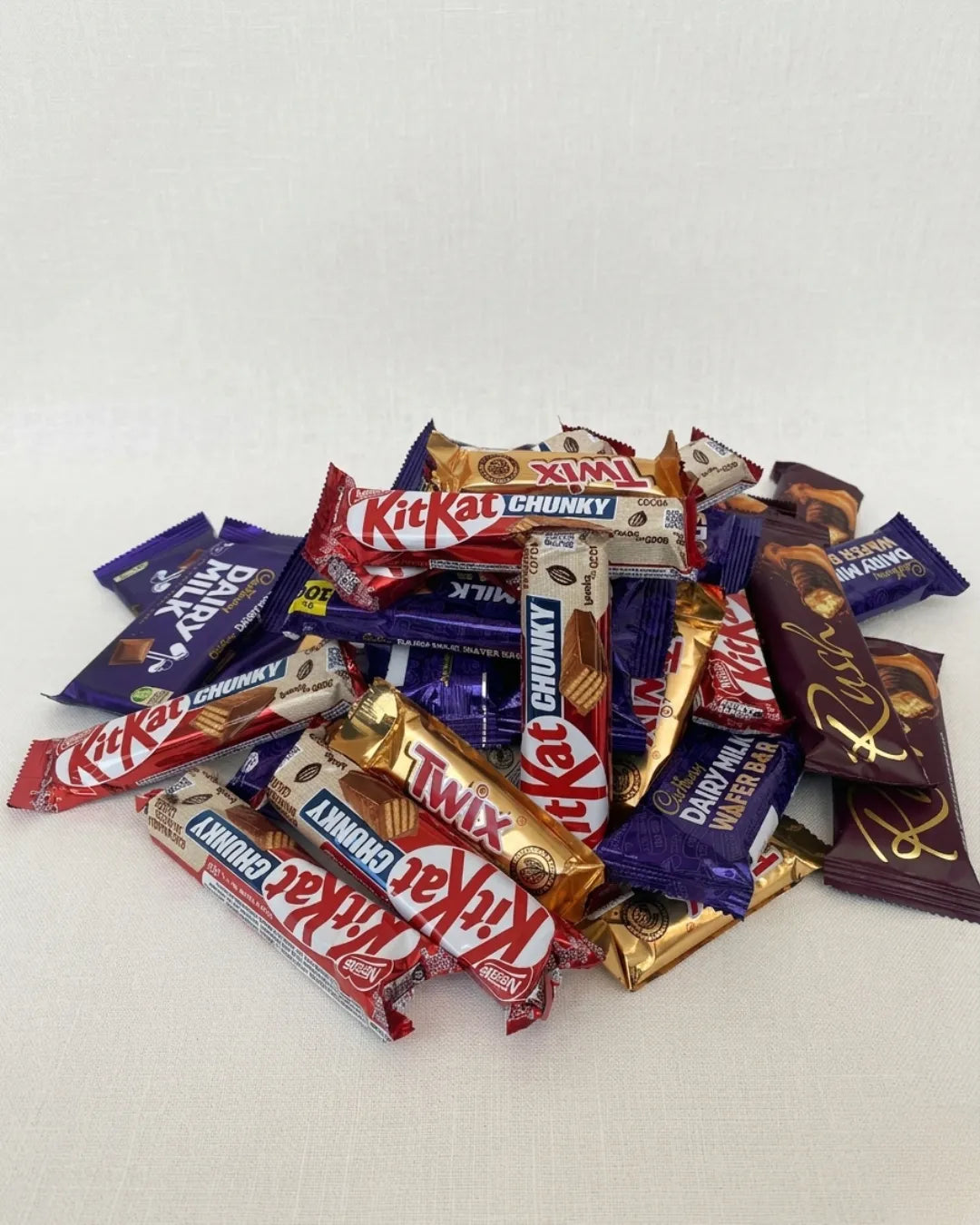 Assorted chocolate candy bars including KitKat, Twix, and Milky Way on a white background