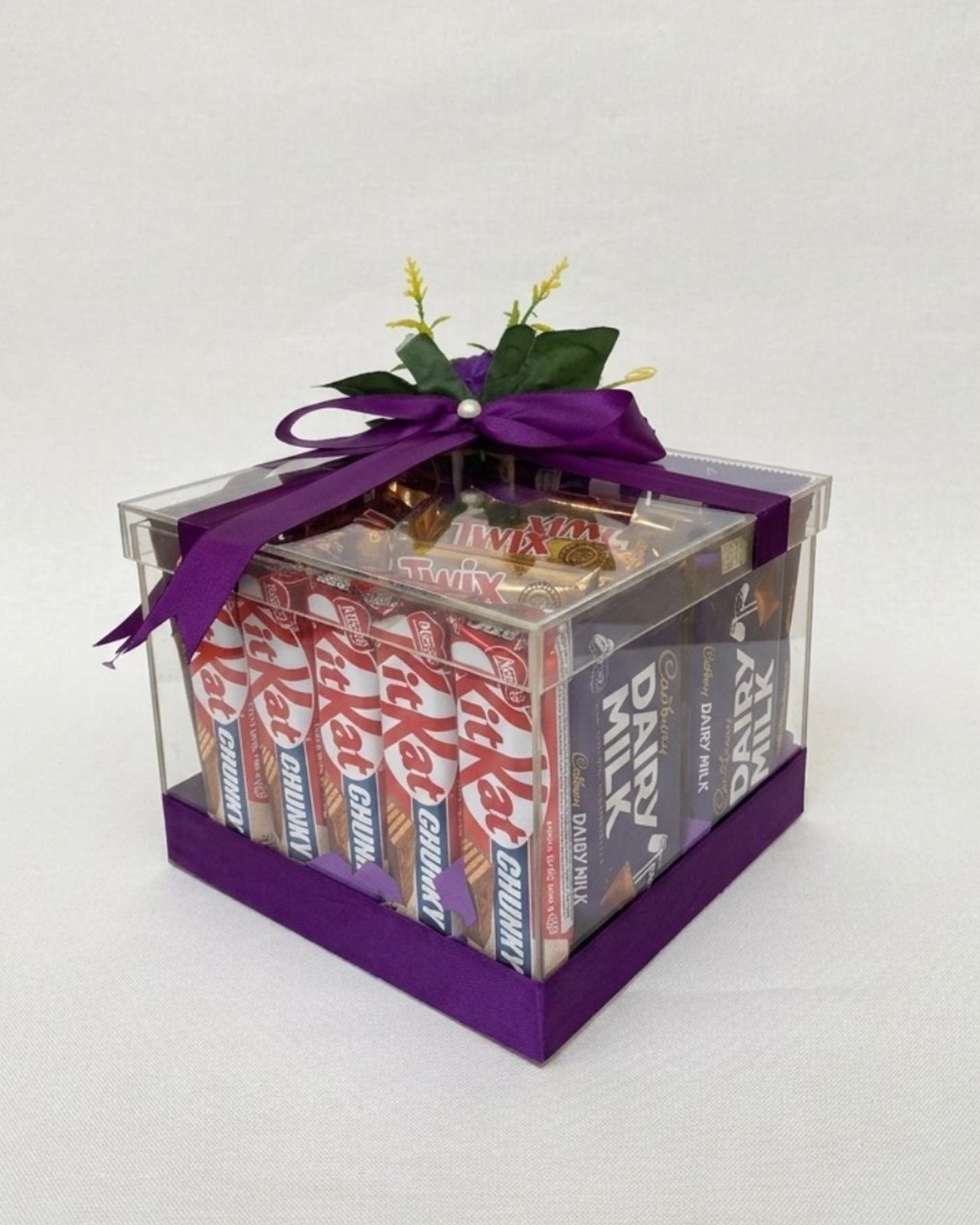 Box of assorted chocolate bars with a purple ribbon on a white background