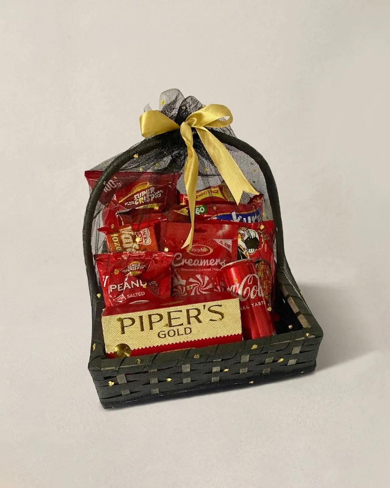Red snacks gift basket with Piper's Gold chocolate, Coca Cola and Super Crisps in black woven basket by The Love Language Pakistan
